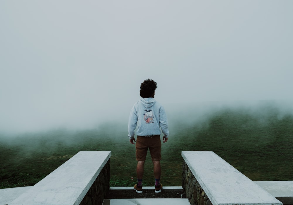 man in blue hoodie standing on wooden dock