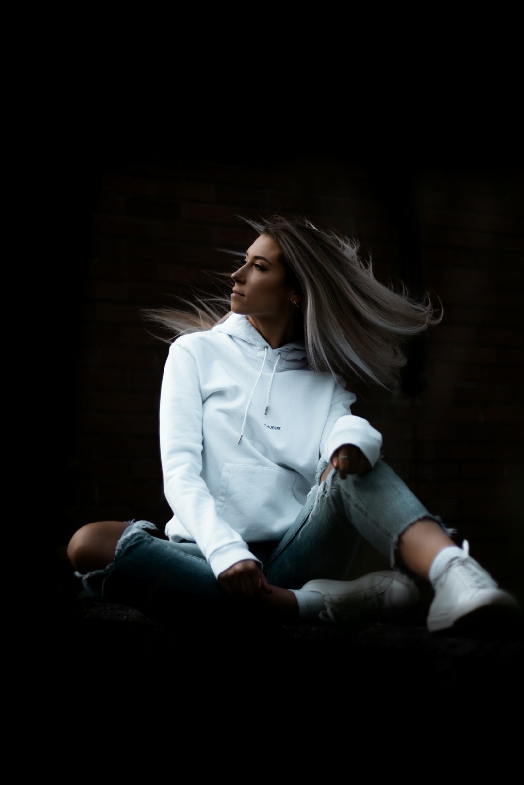 woman in white long sleeve shirt and blue denim jeans sitting on brown wooden floor