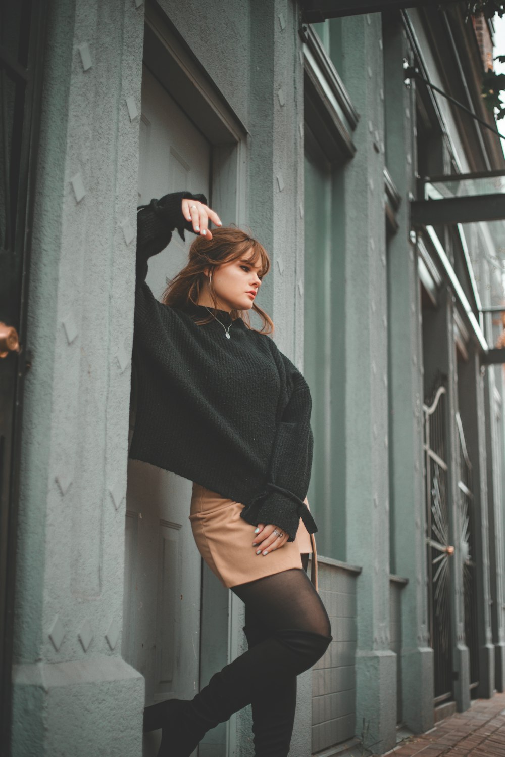 woman in black long sleeve shirt and black shorts standing beside gray wall