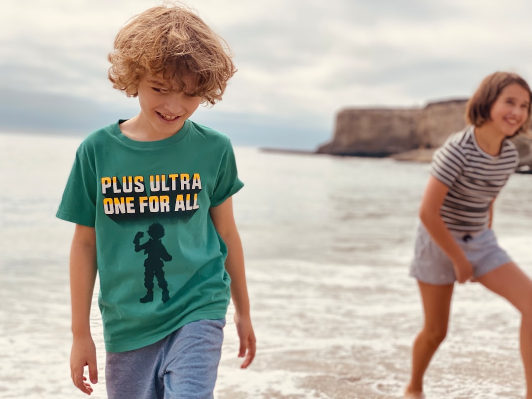 boy in blue crew neck t-shirt standing on beach during daytime