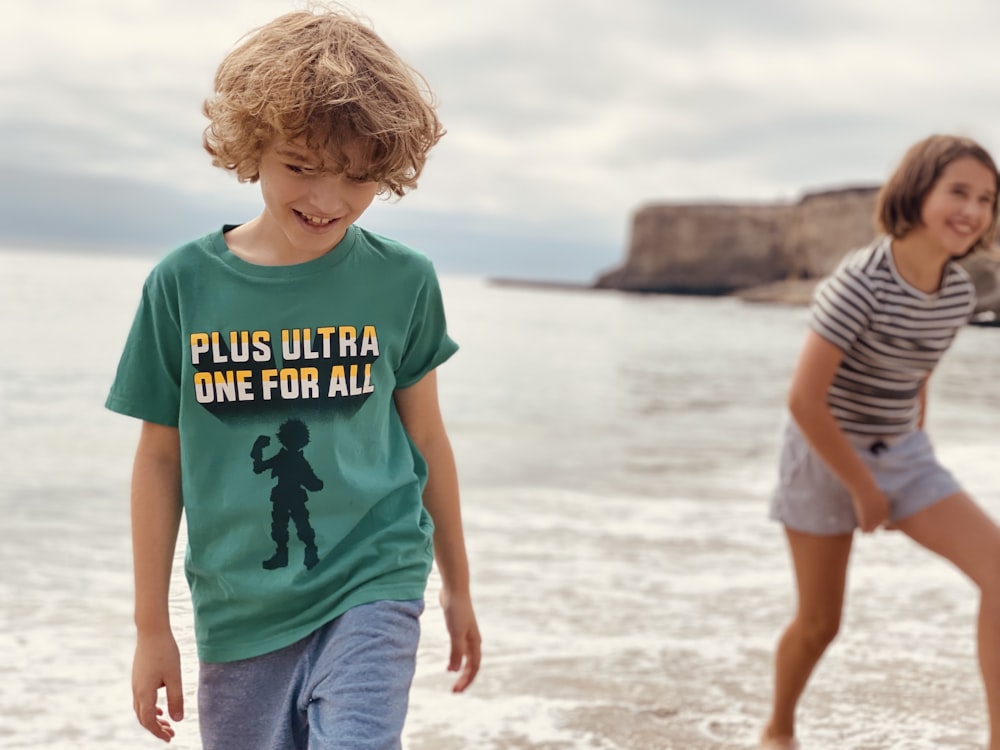 boy in blue crew neck t-shirt standing on beach during daytime