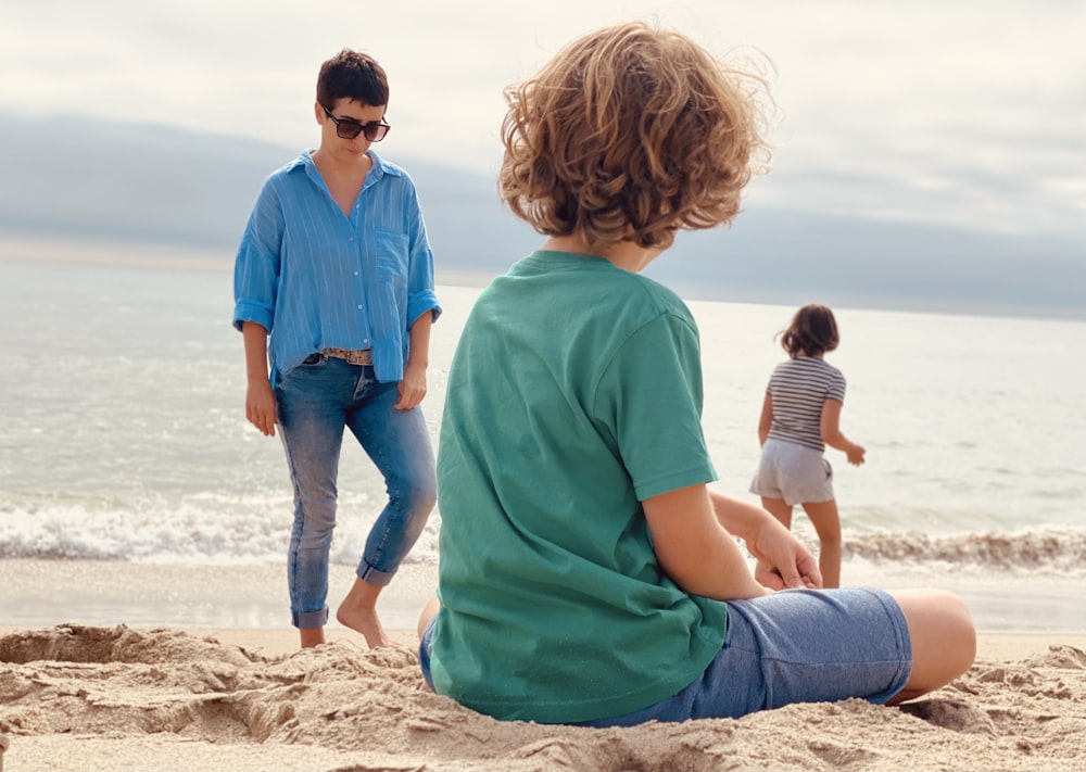 man in teal polo shirt and woman in teal dress on beach during daytime