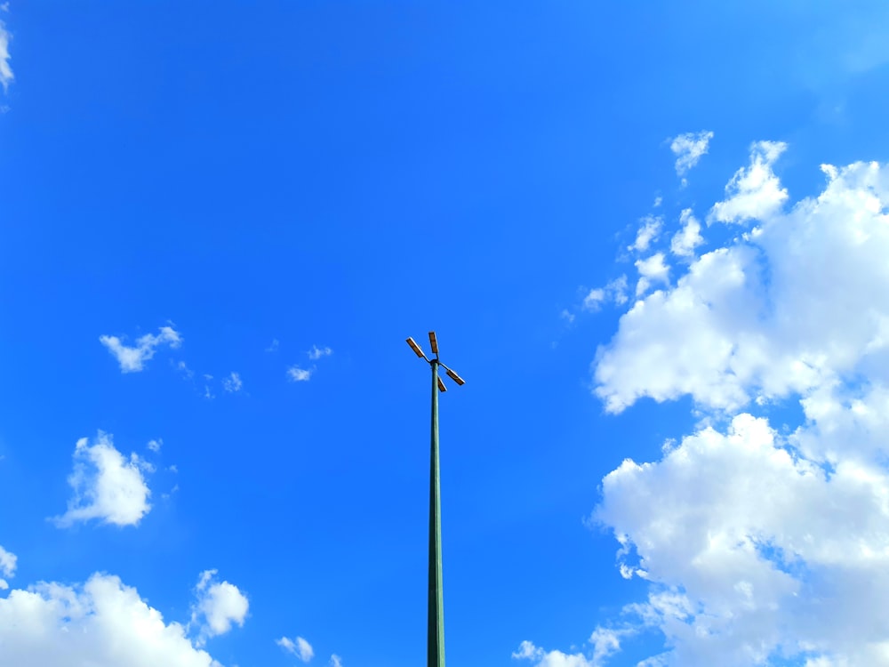 black wind turbine under blue sky and white clouds during daytime