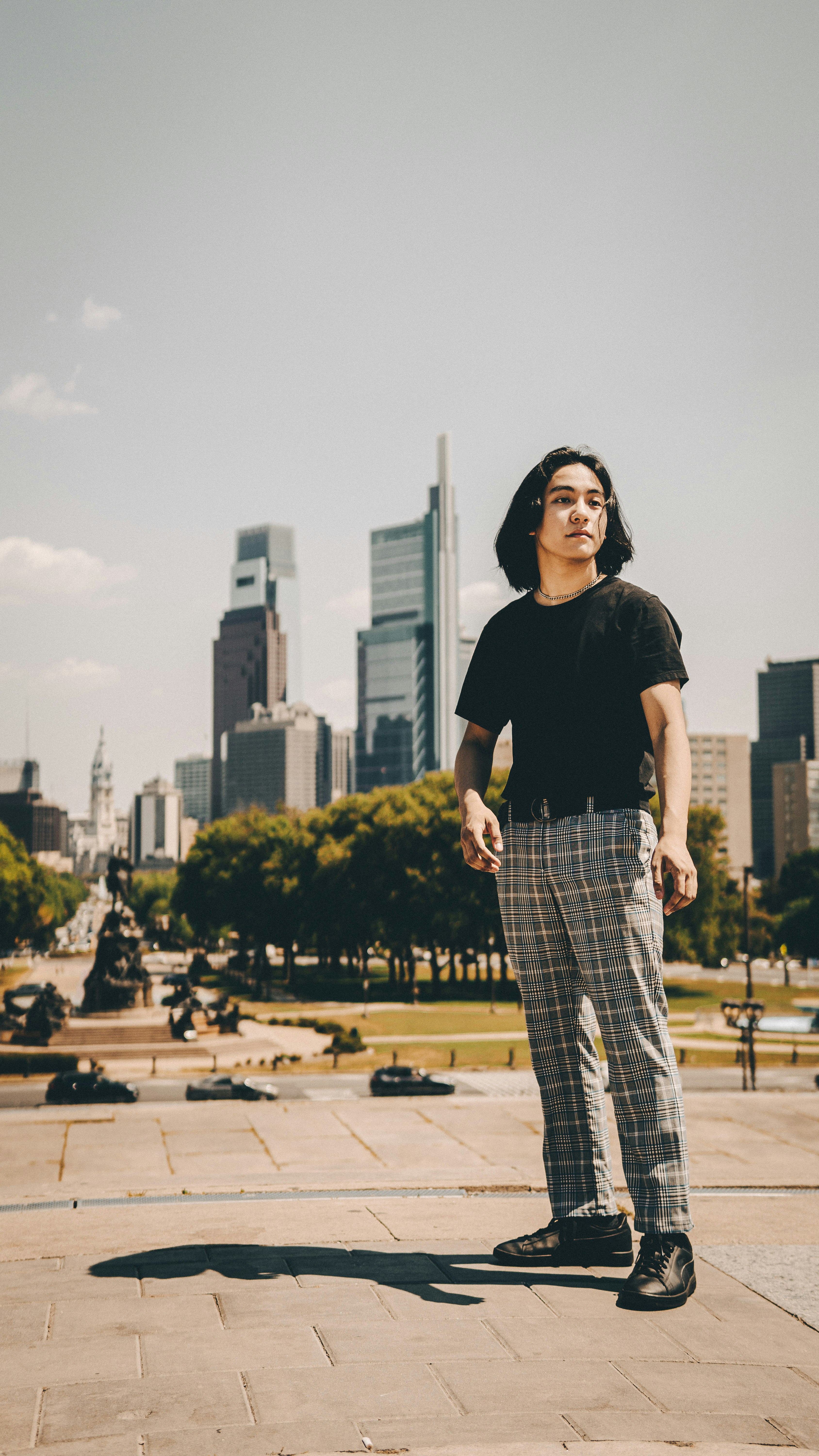 man in black crew neck t-shirt and blue and white plaid pants standing on gray