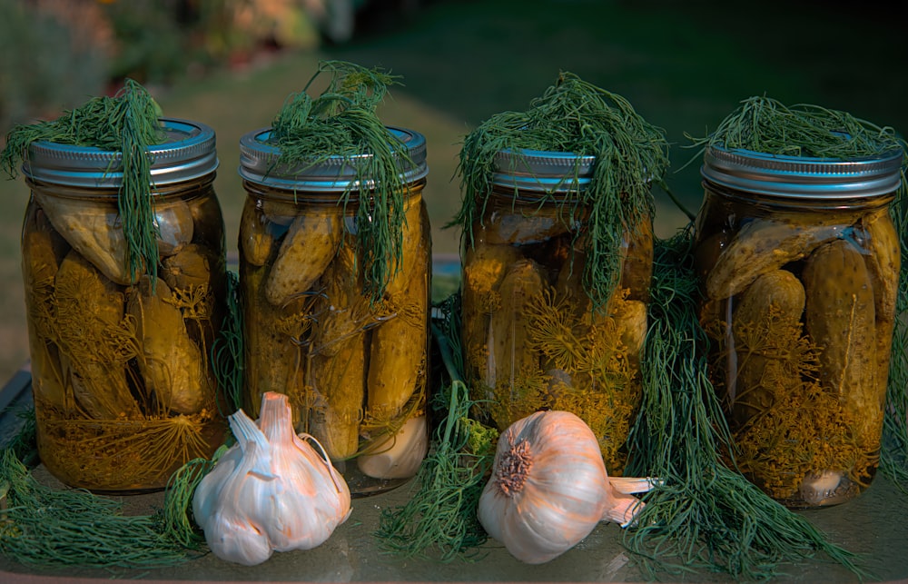 white garlic and green vegetable in clear glass jar