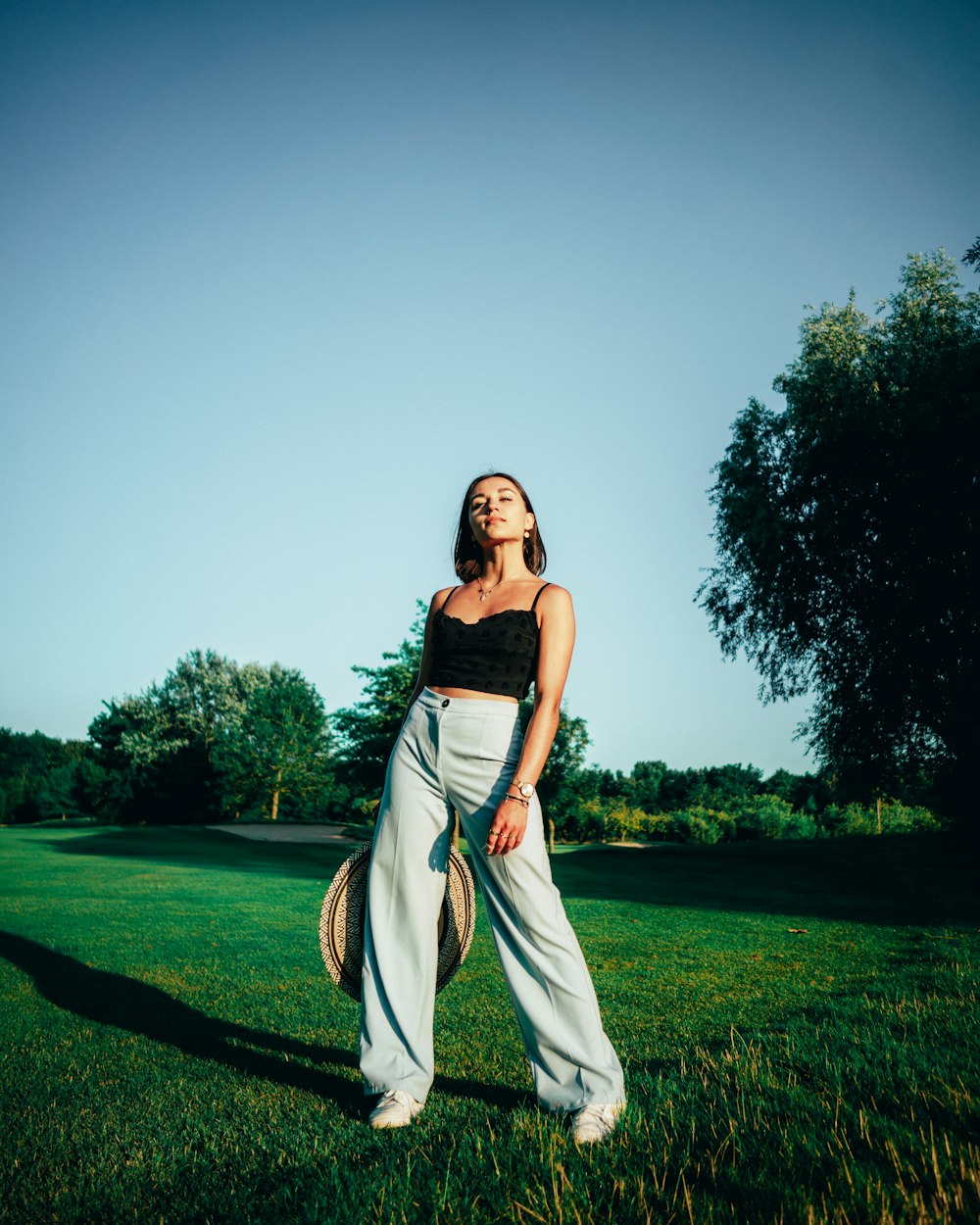 woman in black and white dress standing on green grass field under gray sky during daytime