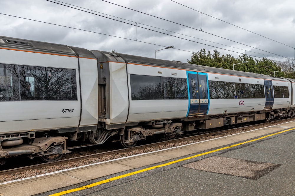 white and blue train on rail tracks under white clouds during daytime