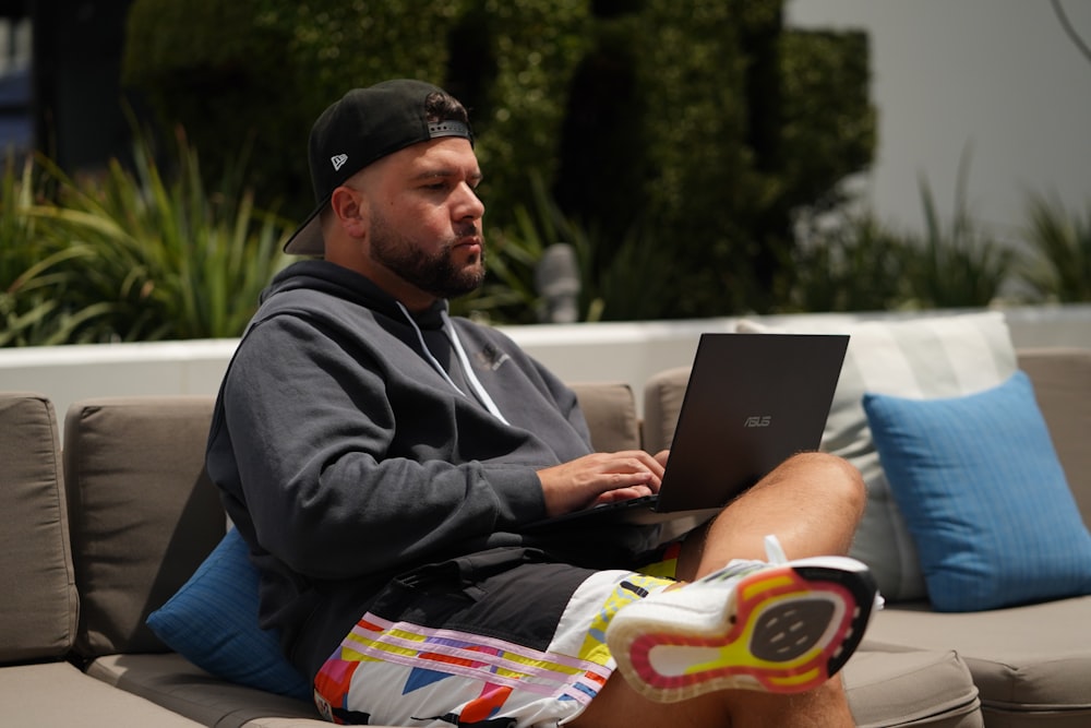 man in black hoodie sitting on floor using macbook
