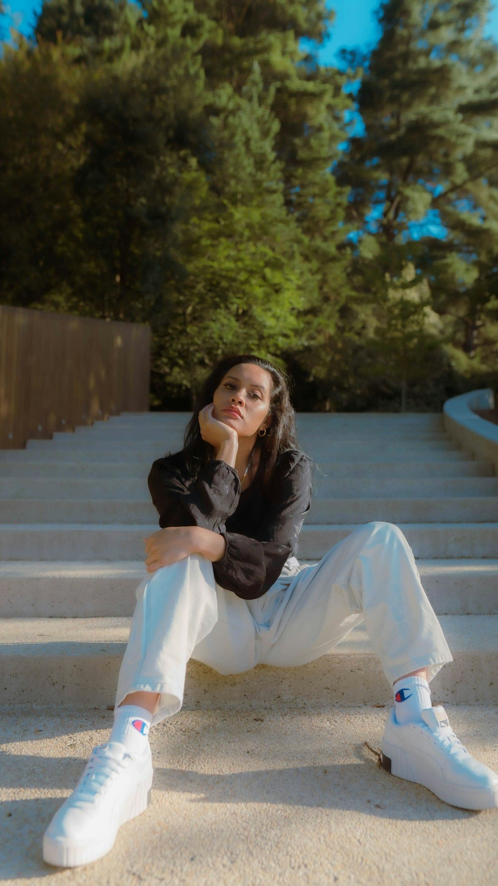 woman in gray jacket and white pants sitting on concrete stairs