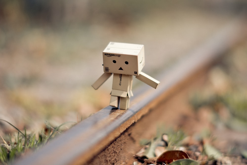 brown cardboard robot on brown wooden fence