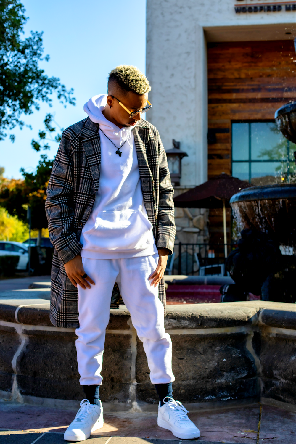 man in white pants and black and white checkered dress shirt standing on gray concrete floor