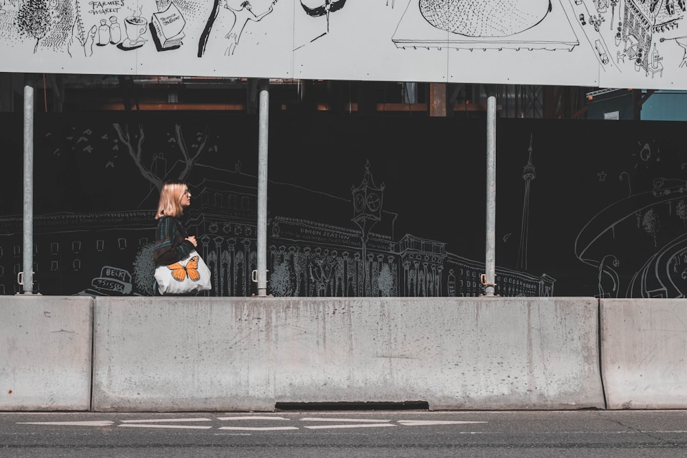 woman in white jacket sitting on gray concrete bench