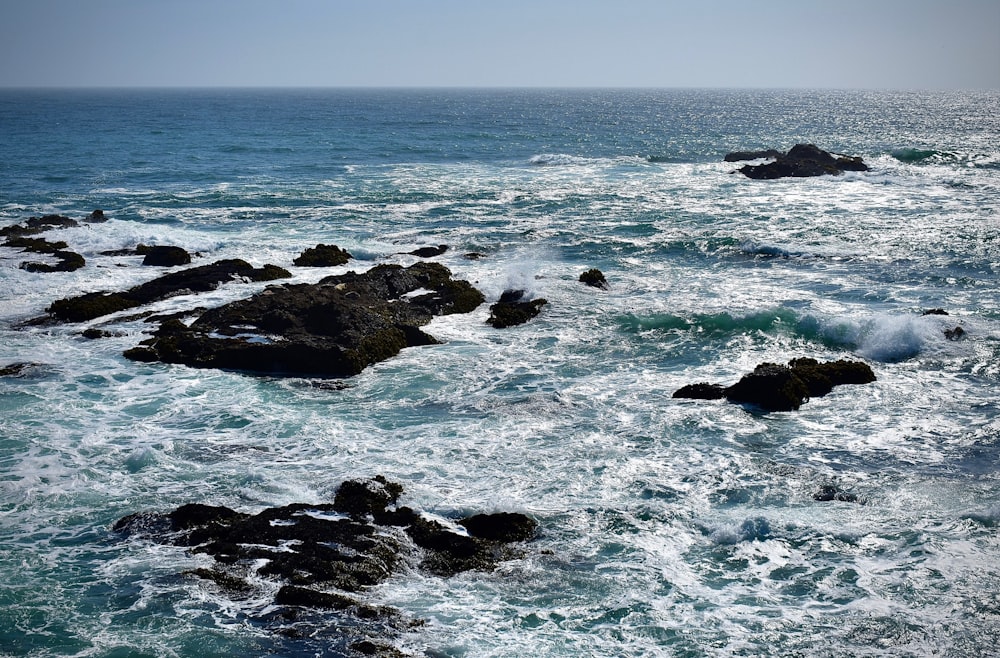 ocean waves crashing on rocks during daytime