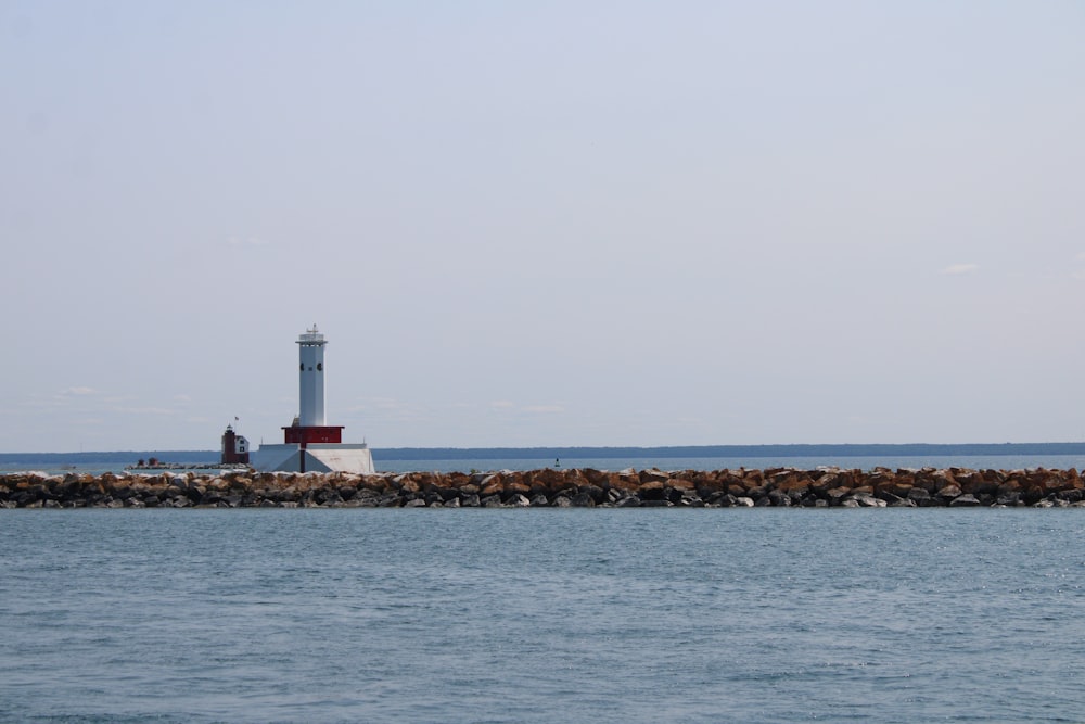 Weißer Leuchtturm in der Nähe des Gewässers tagsüber