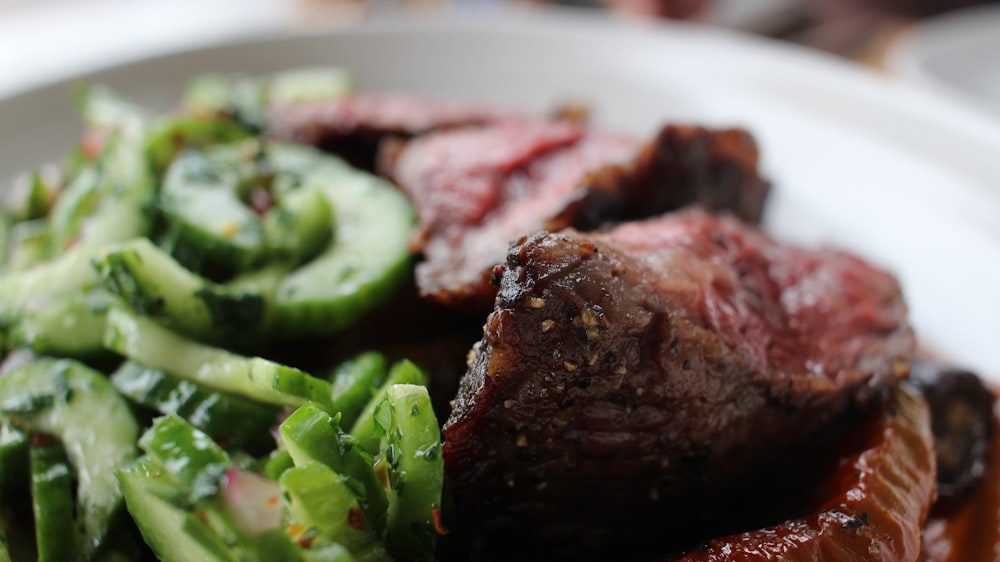 grilled meat with green vegetable on white ceramic plate