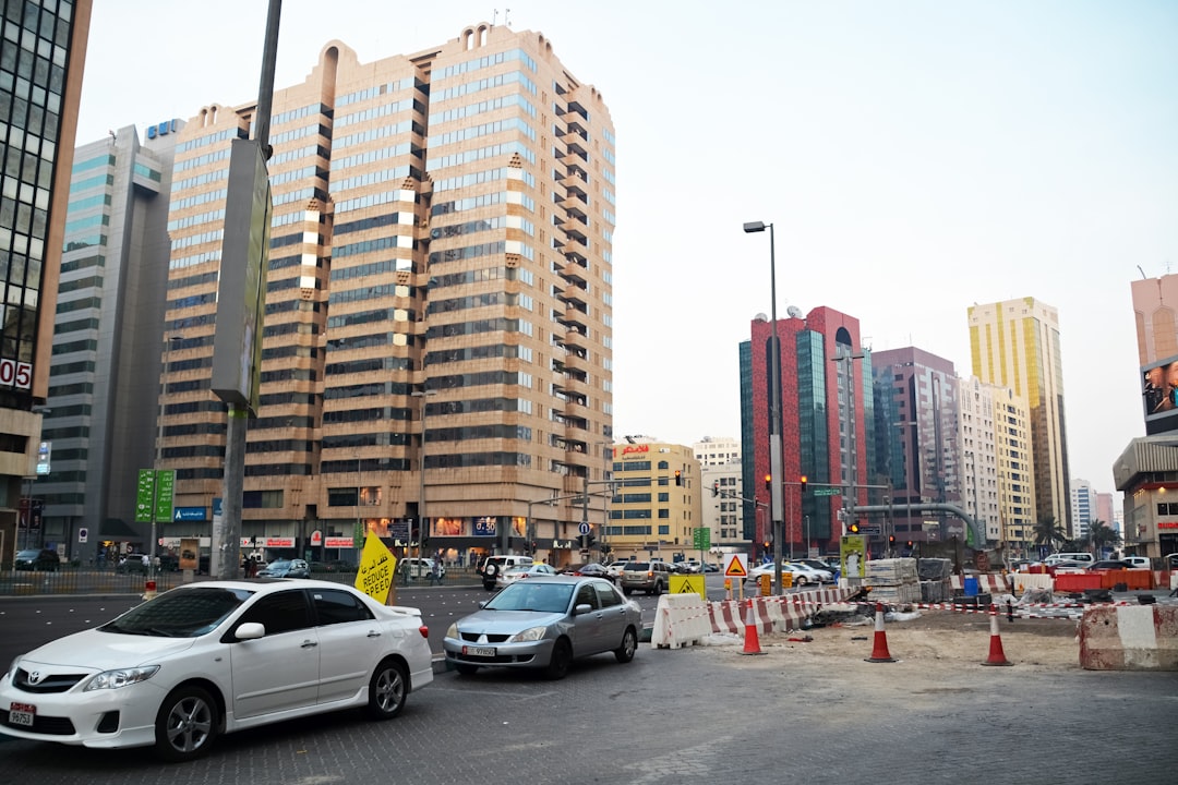 cars parked on parking lot near high rise buildings during daytime