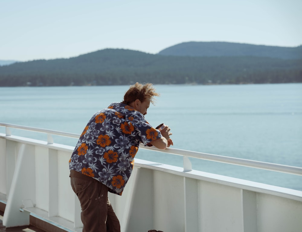 woman in blue and white floral shirt standing on white wooden railings during daytime