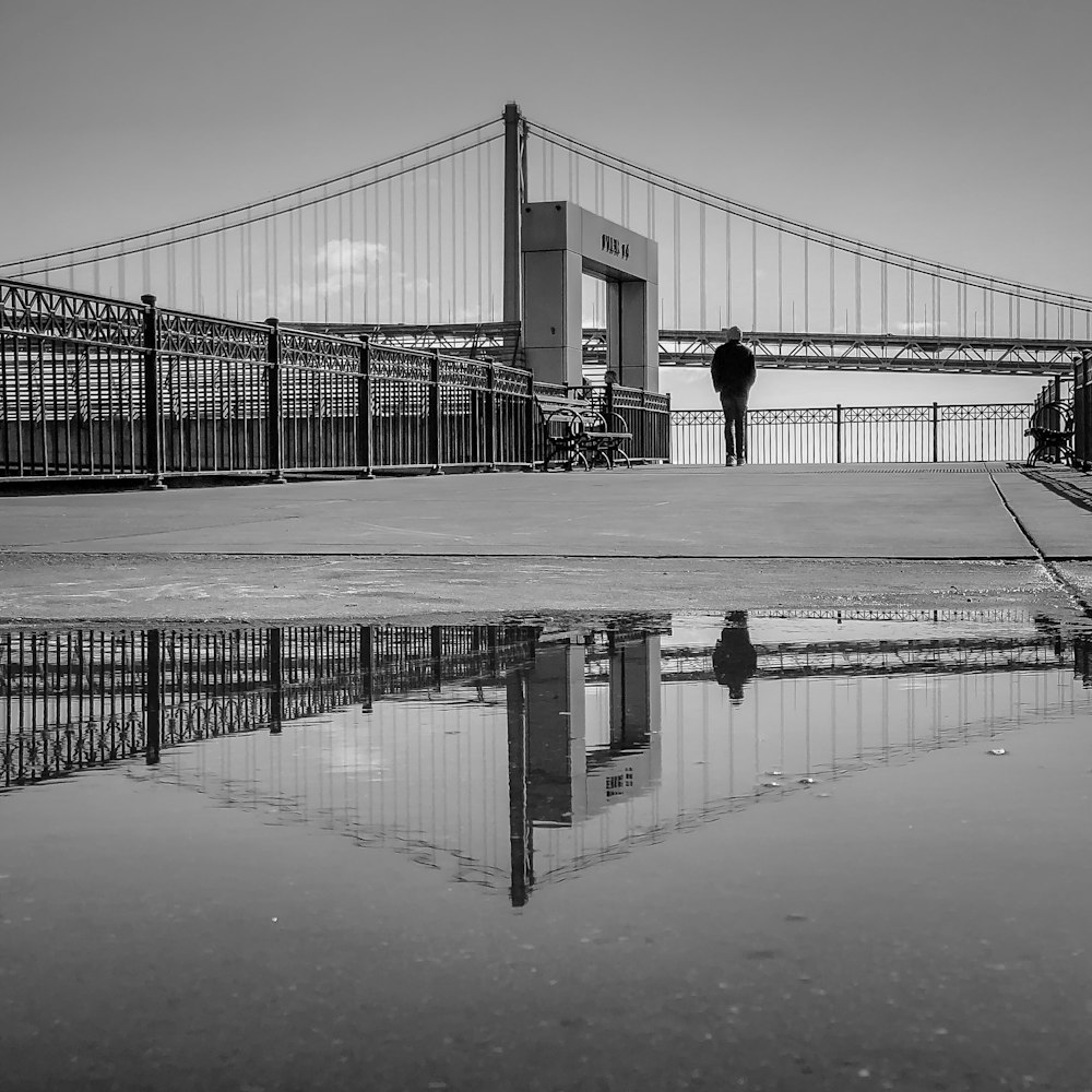 foto em tons de cinza de pessoas andando na ponte