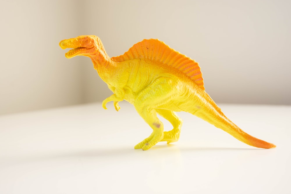 yellow dinosaur plastic toy on white table