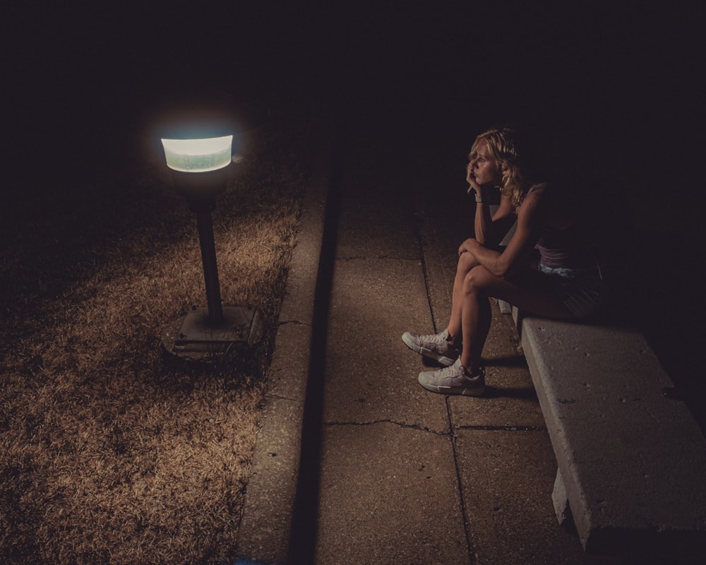 femme en débardeur noir assise sur le sol en béton