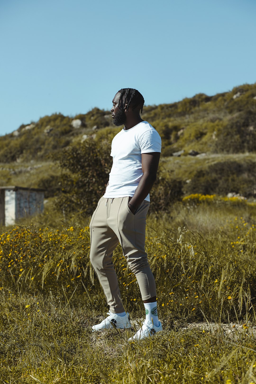 woman in white t-shirt and white pants walking on green grass field during daytime