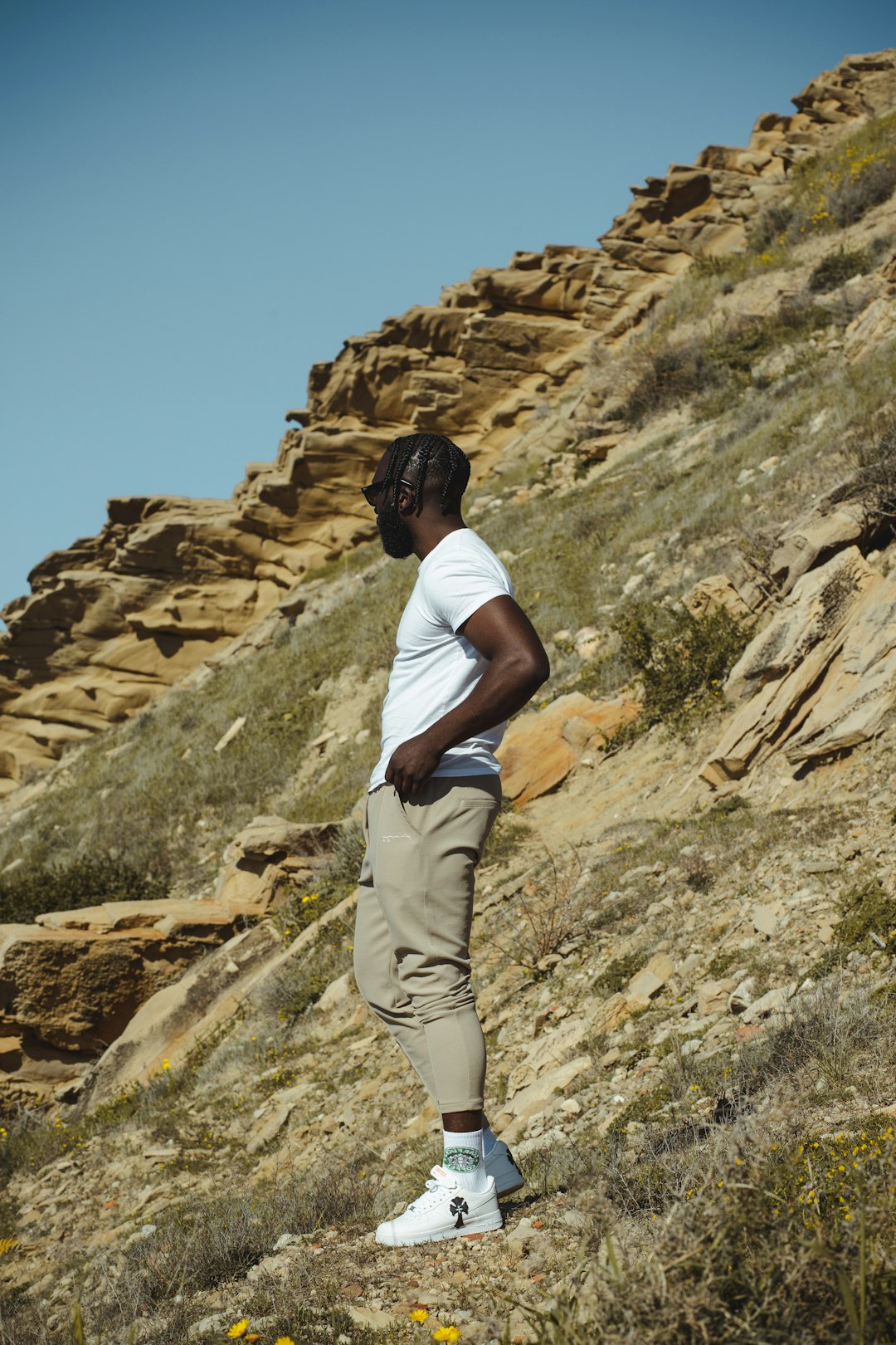 woman in white t-shirt and white pants standing on rocky mountain during daytime