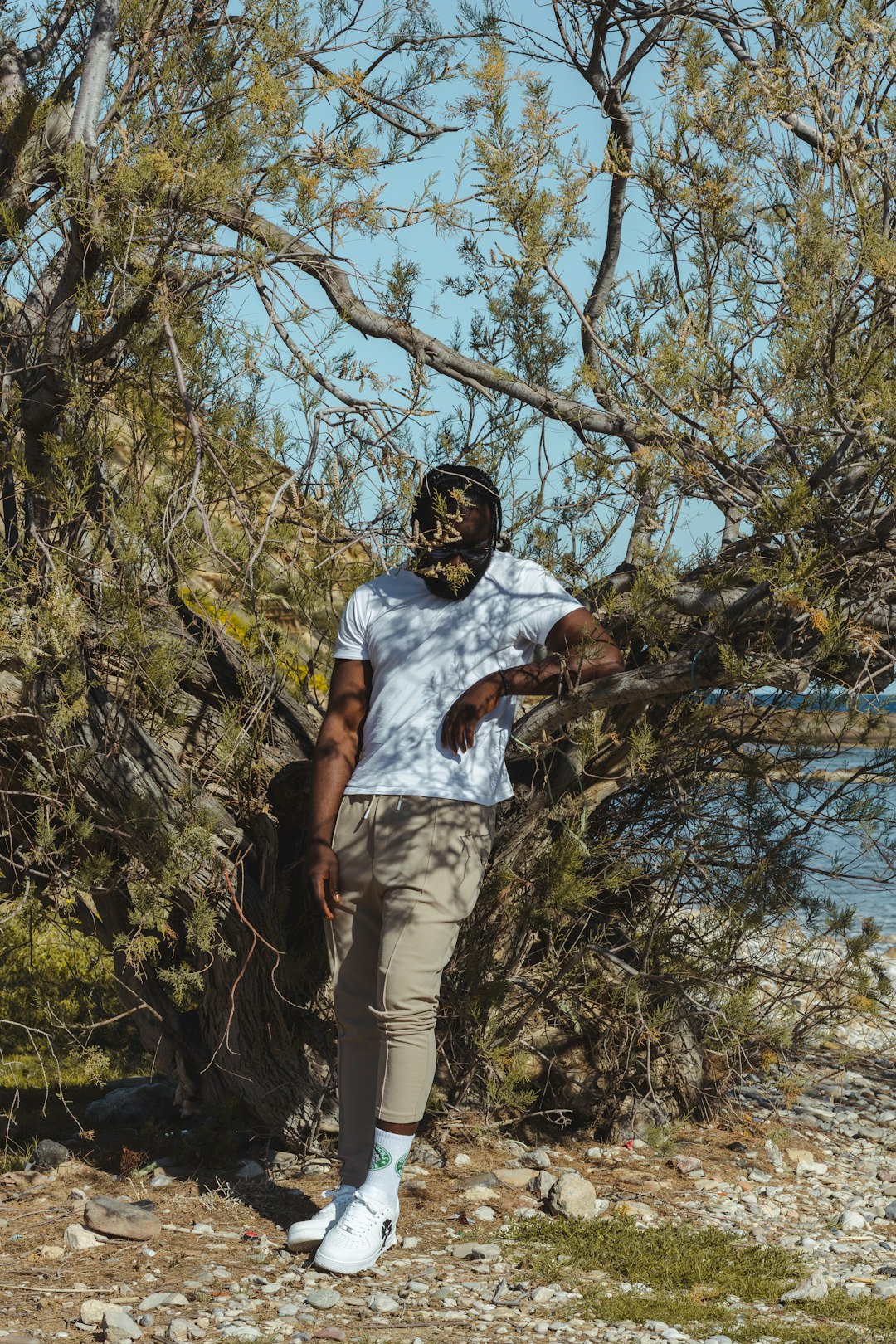 man in white crew neck t-shirt and brown cargo shorts standing on brown tree branch