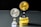 Two coins labeled 'EXU' are standing upright on holders. One is silver and placed on a silver stand, the other is gold and placed on a stack of gold coins. The coins feature leaf designs.