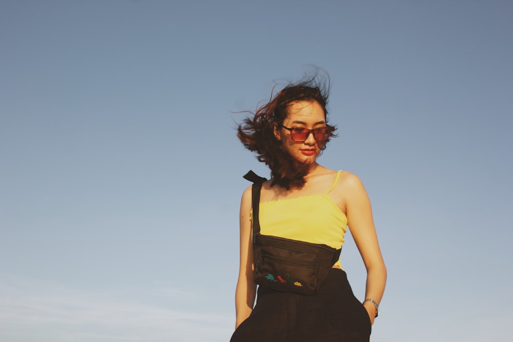 woman in yellow tank top and black skirt standing under blue sky during daytime