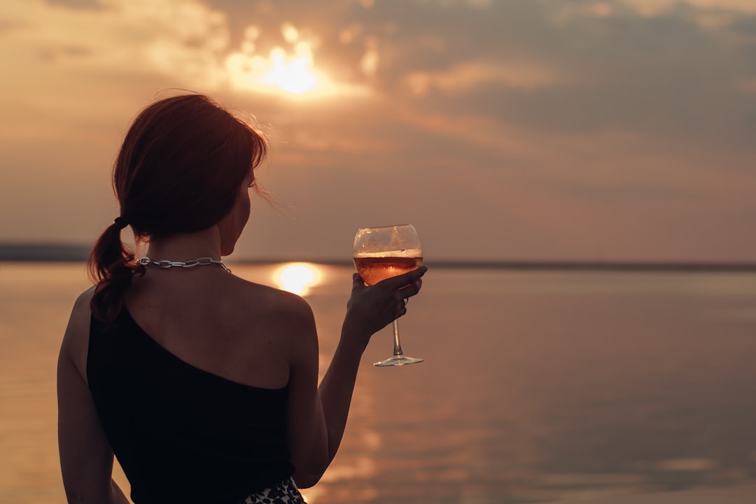 woman in black tank top holding clear wine glass during sunset