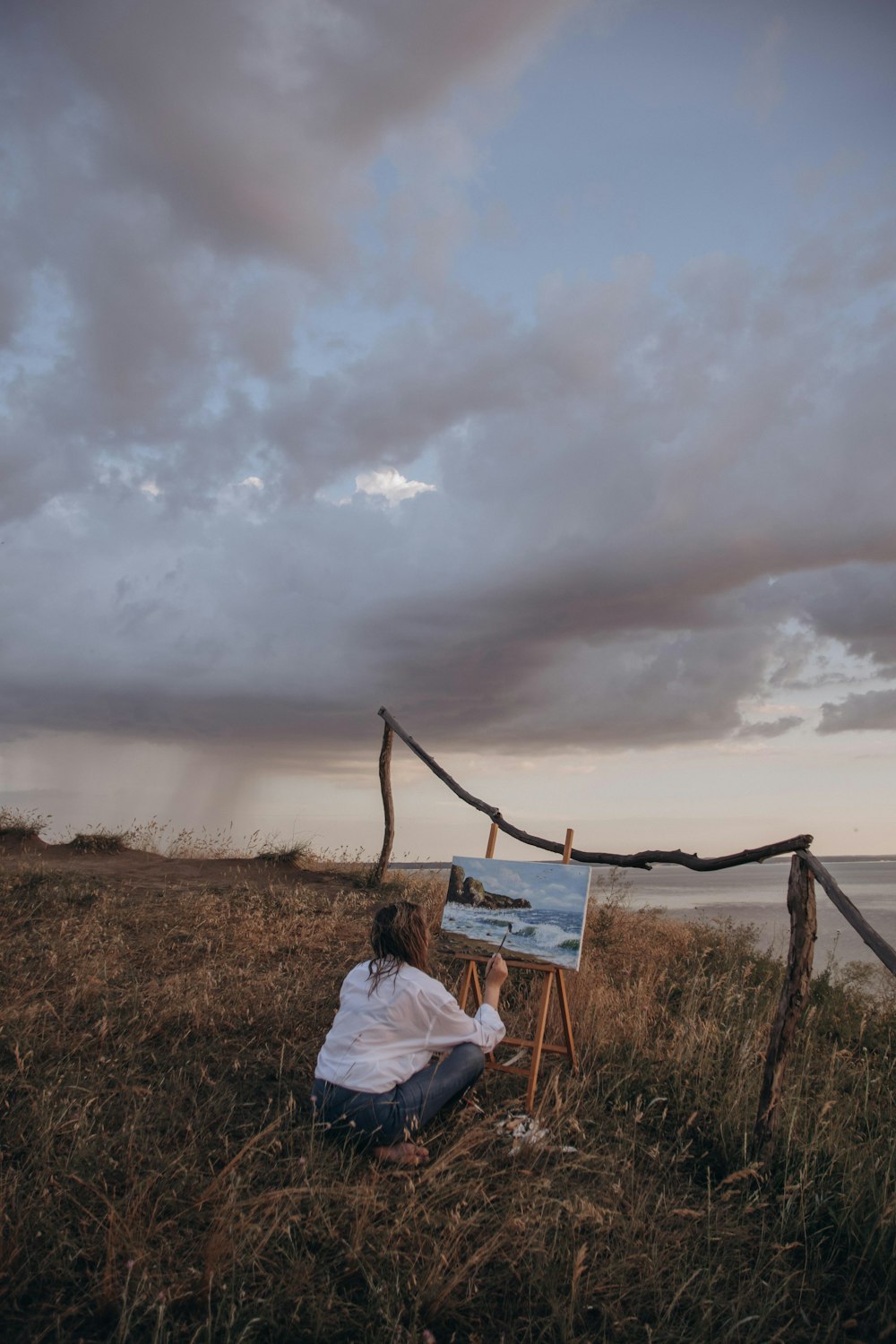 person in white shirt sitting on brown wooden ladder on green grass field under white clouds