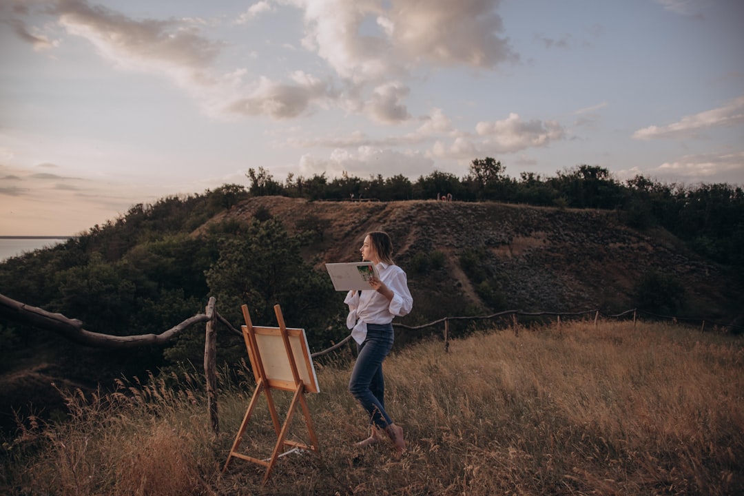 woman in white long sleeve shirt and blue denim jeans standing on green grass field during