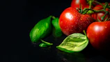 Fresh basil leaves glistening with droplets of olive oil on a rustic wooden table.