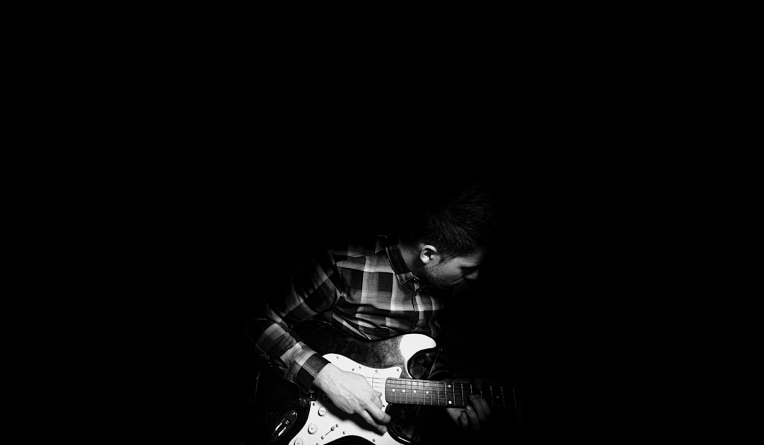 man playing guitar in grayscale photography