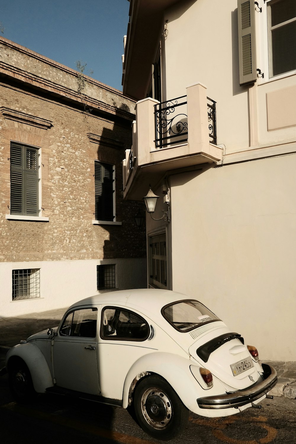 white car parked beside brown concrete building during daytime