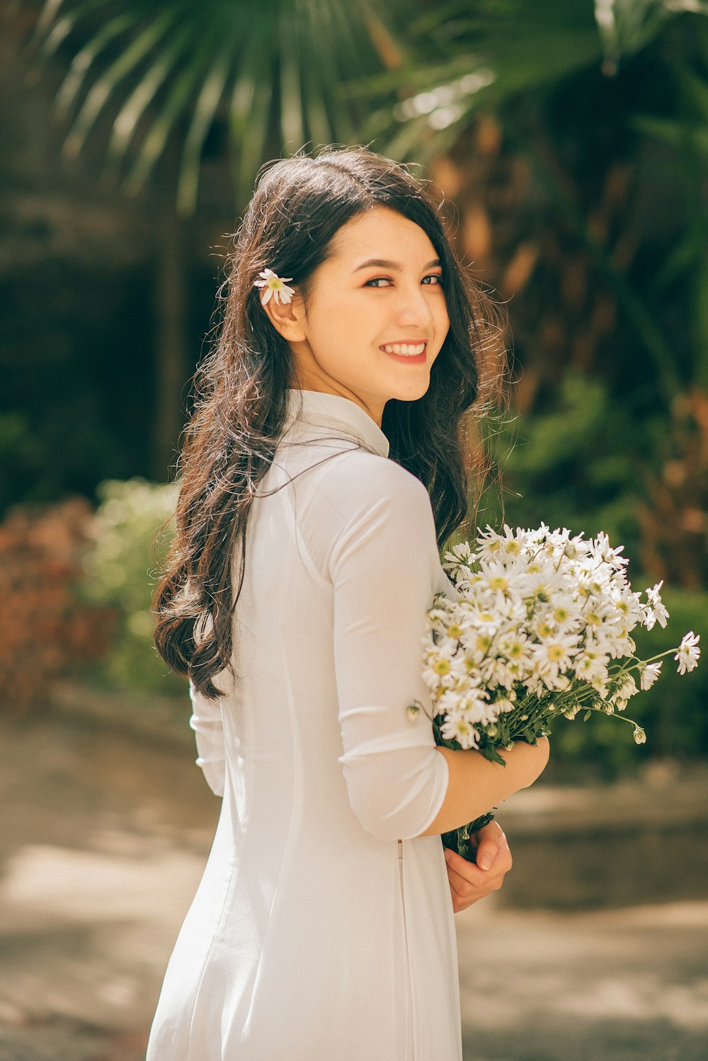 woman in white long sleeve shirt holding white flowers