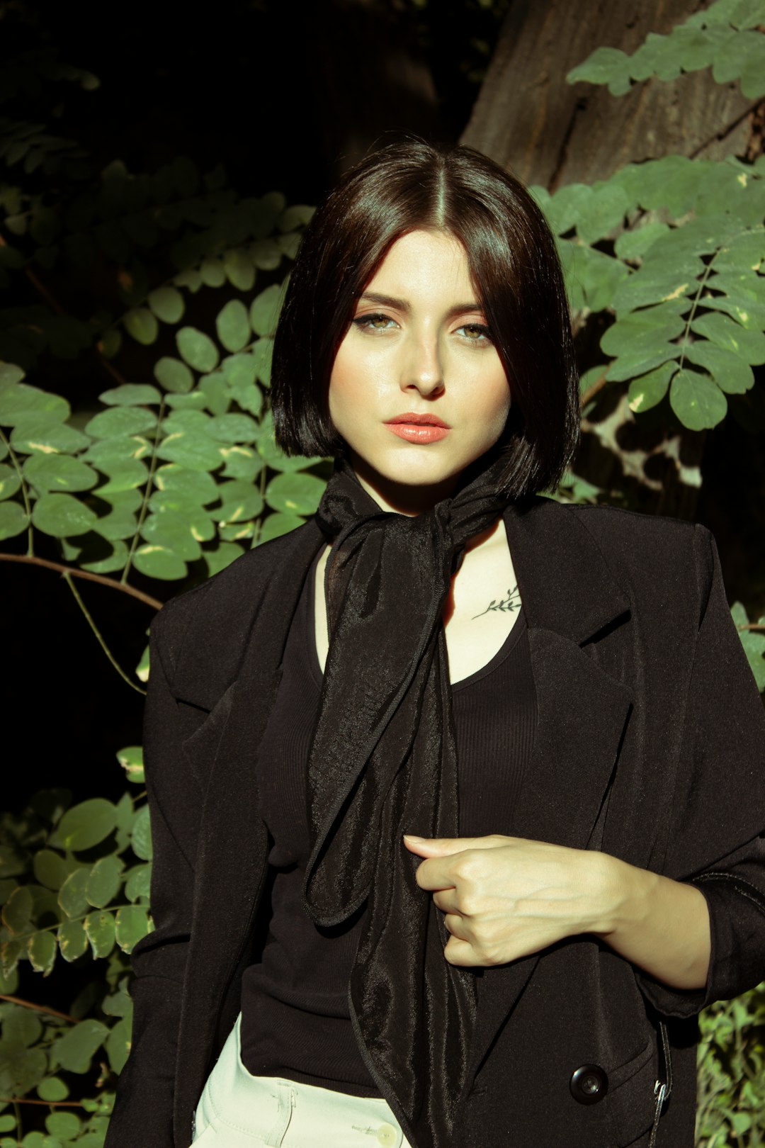 woman in black blazer standing near green leaves