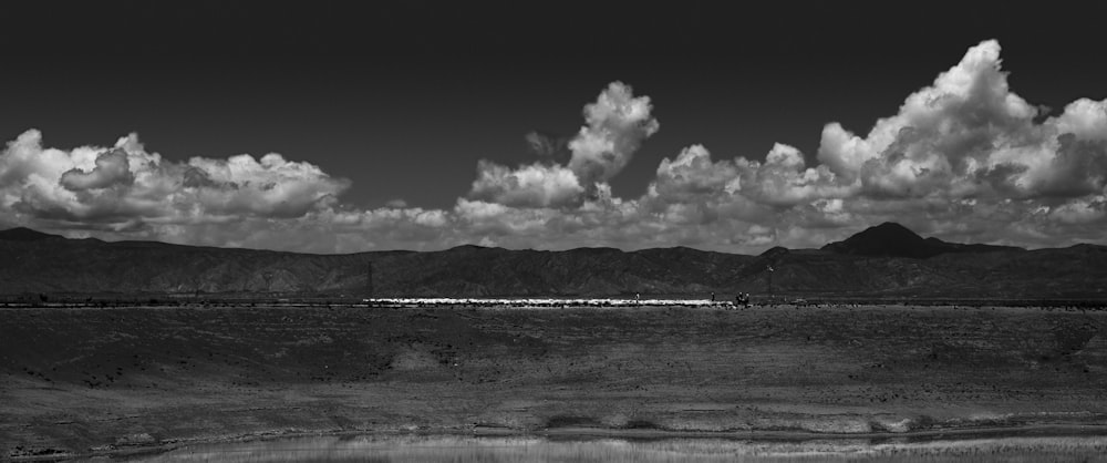 grayscale photo of people on beach under cloudy sky