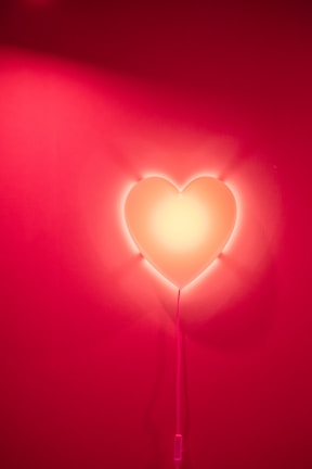 A cozy living room softly illuminated by a warm pink neon heart.