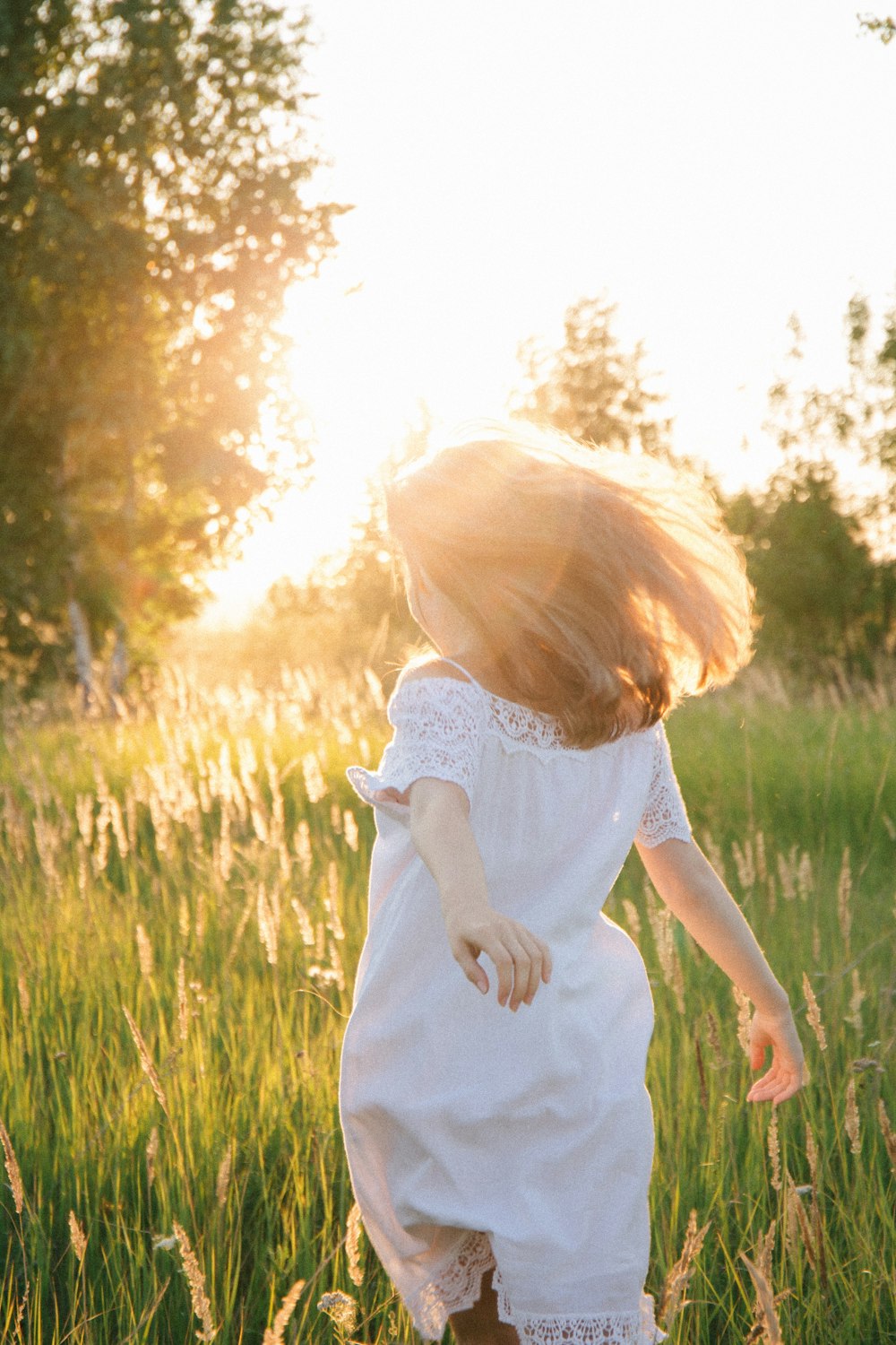 girl in white dress standing on green grass field during daytime