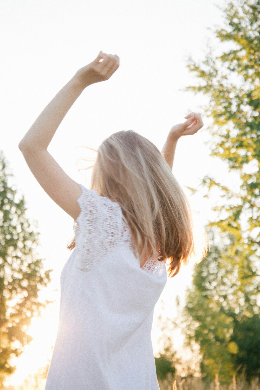 woman in white floral dress raising her hands