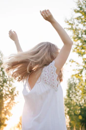 woman in white floral sleeveless dress raising her hands