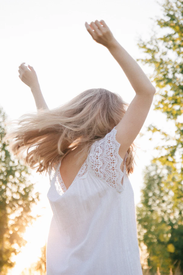 woman in white floral sleeveless dress raising her hands
