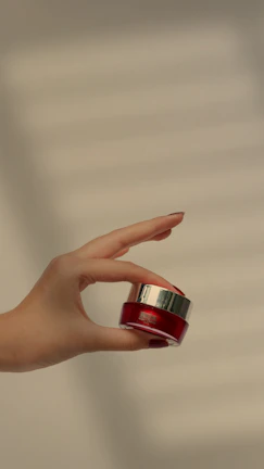 Close-up of hands holding a small jar of herbal balm with soft natural light