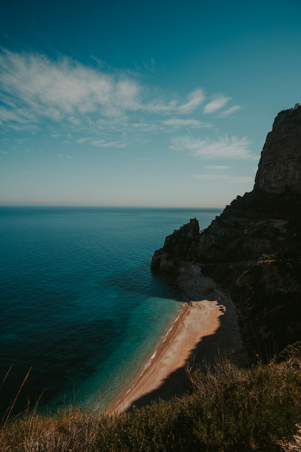 brown rock formation beside blue sea under blue sky during daytime