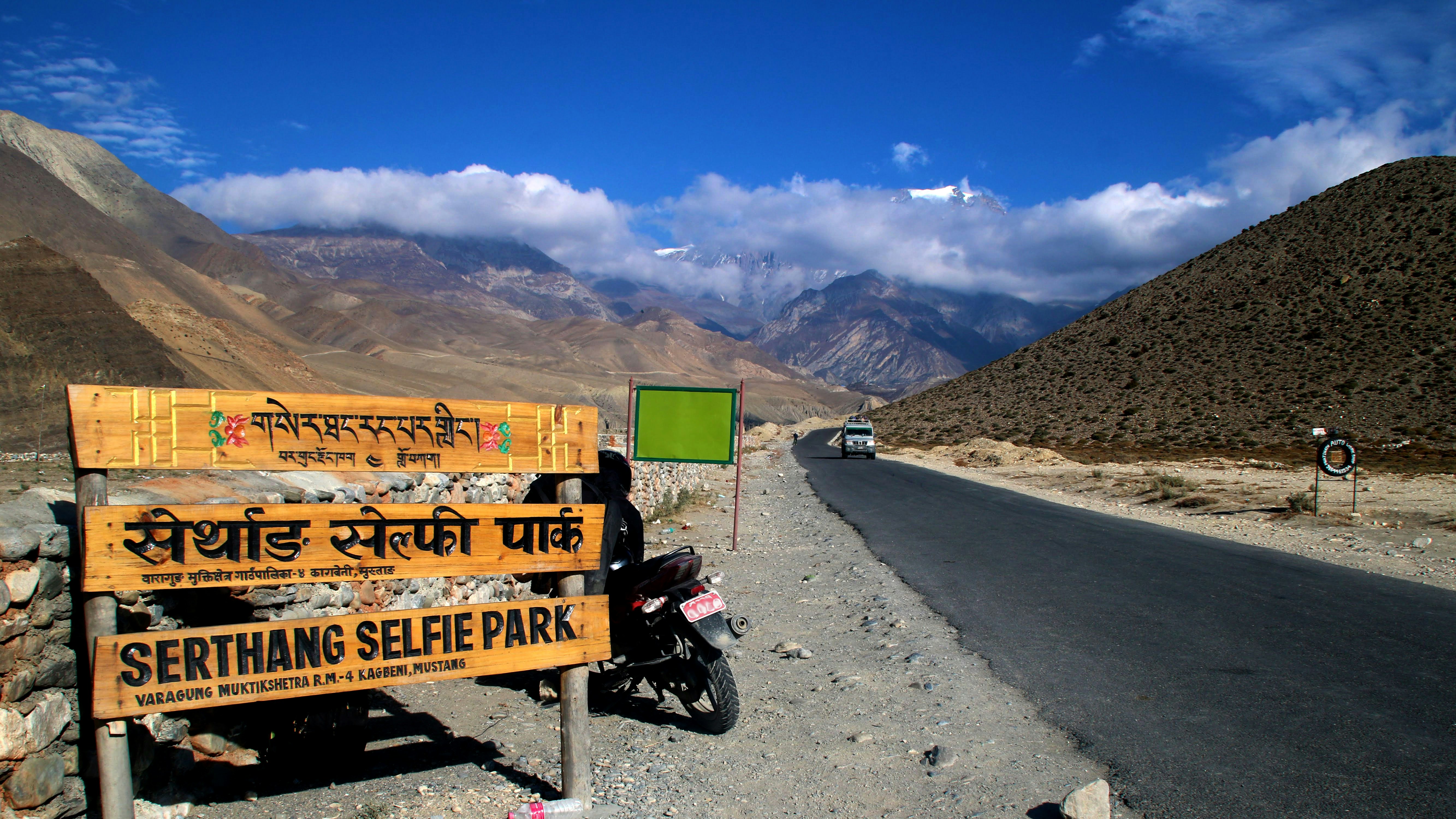 gündüz vakti kahverengi ahşap bankın yanında park etmiş siyah motosiklet