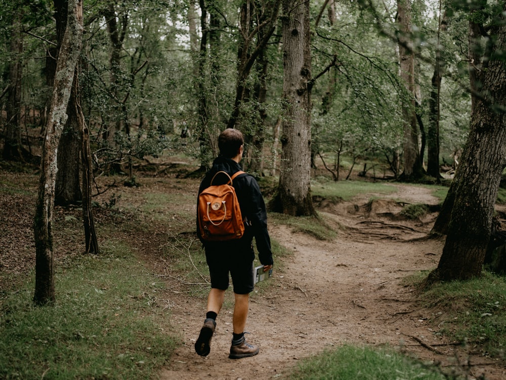 woman in black and red jacket walking on forest during daytime