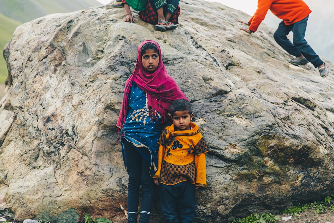 woman in red hijab standing on rocky mountain during daytime