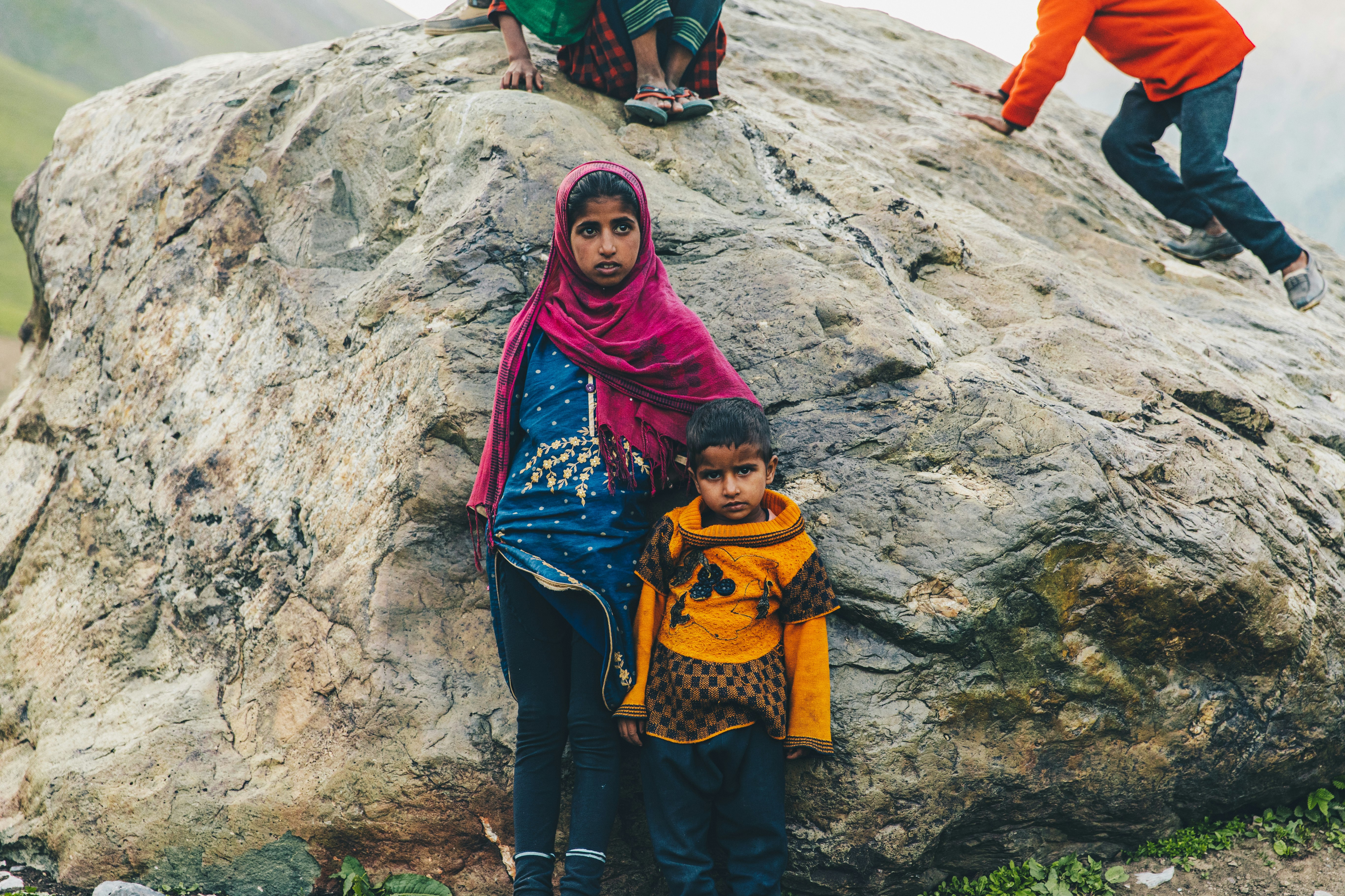 woman in red hijab standing on rocky mountain during daytime