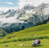 person riding motorcycle on green grass field near snow covered mountain during daytime